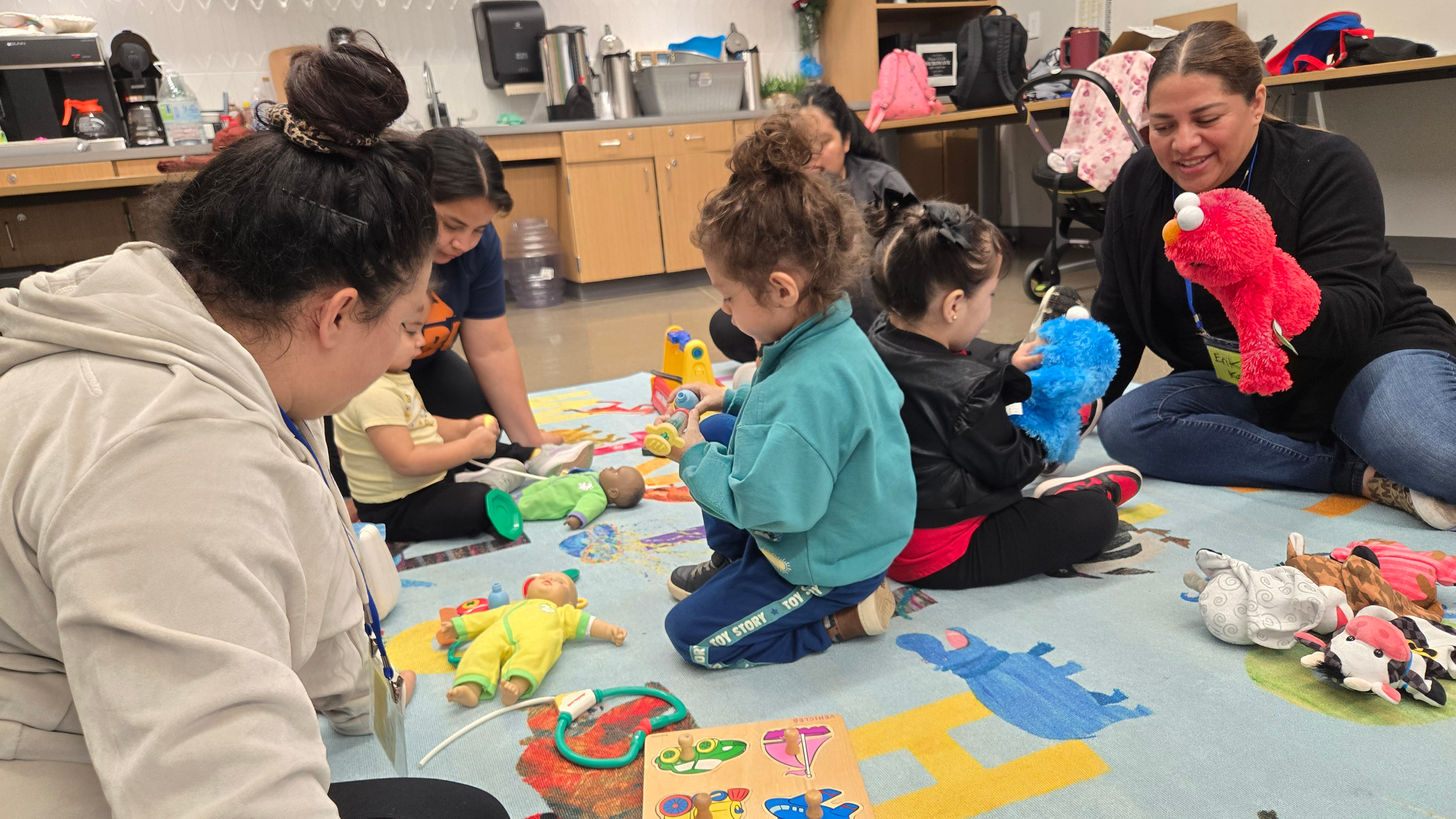 A group of educators and young students learn with Sesame Street characters Elmo and Grover
