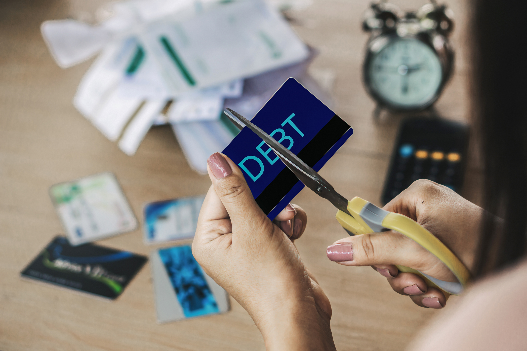 woman hand cutting credit cards by scissors with calculator and financial bills on desk