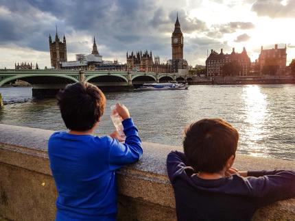 Two boys look across the river to the Houses of Parliament.