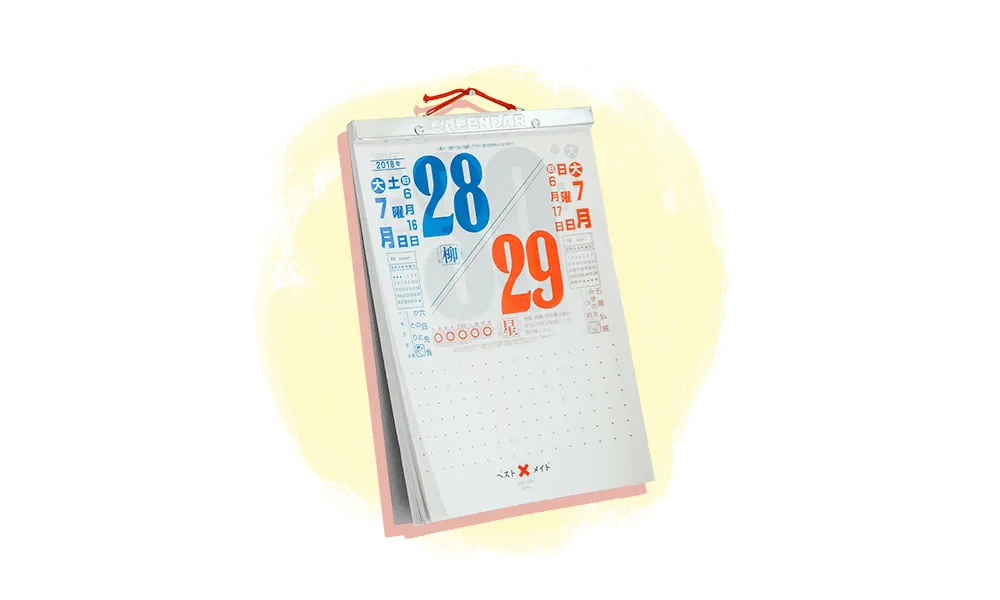Ein stehender Tischkalender mit den Daten 28 und 29 in großen blauen und orangefarbenen Zahlen, mit japanischem und englischem Text auf weißem Hintergrund.
