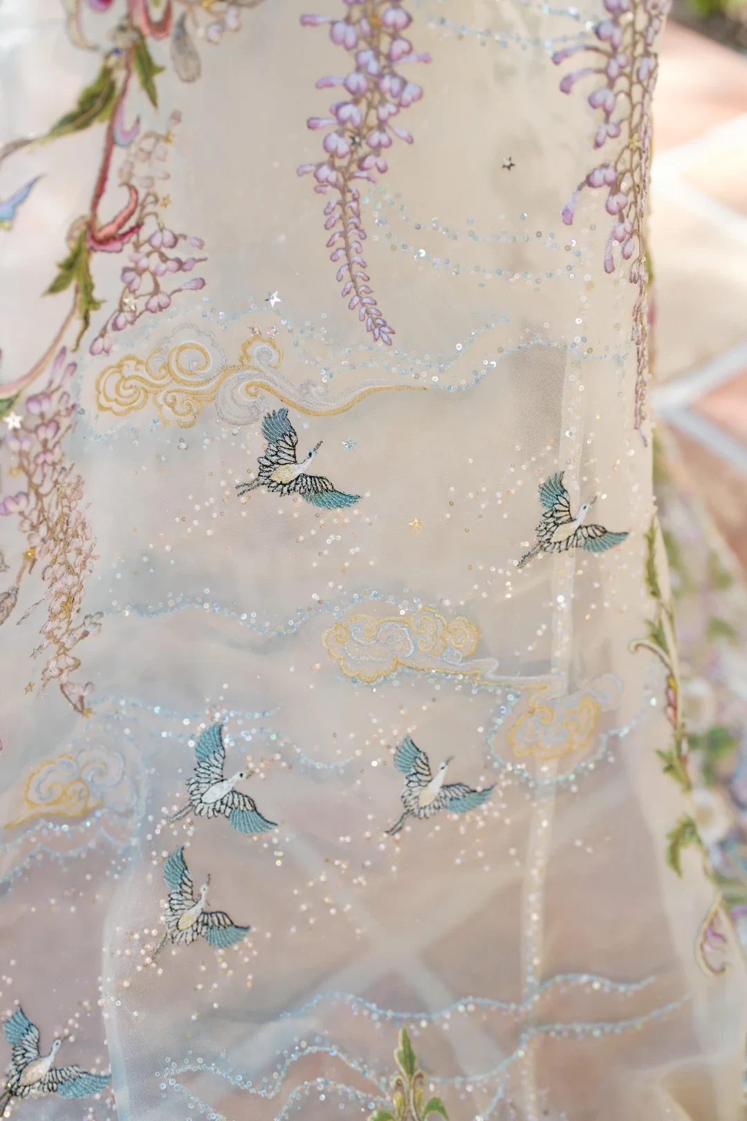 Embroidered sequins catch the light to make the cloud ridges shimmer.