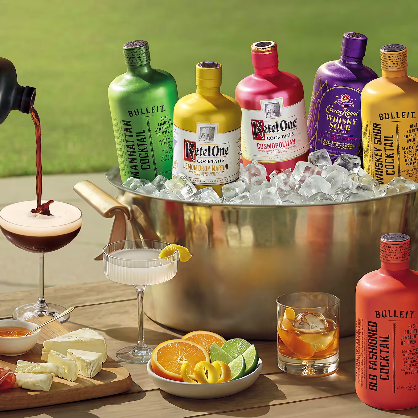 Collection of ready-to-drink cocktails from Bulleit, Ketel One, and Crown Royal displayed on ice with served cocktails, citrus slices, and appetizer pairings. Premium bottled cocktail selection ideal for entertaining, gifting, parties, and convenient cocktail enjoyment.