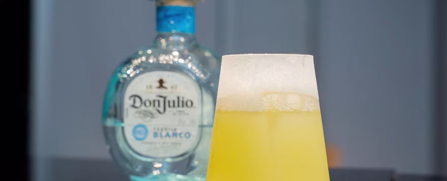 La imagen muestra una botella de tequila Don Julio Blanco junto a un vaso con un cóctel llamado "Margarita Costera" creado por el finalista de World Class 2024 Perú, Rolando Arias de Troppo.
