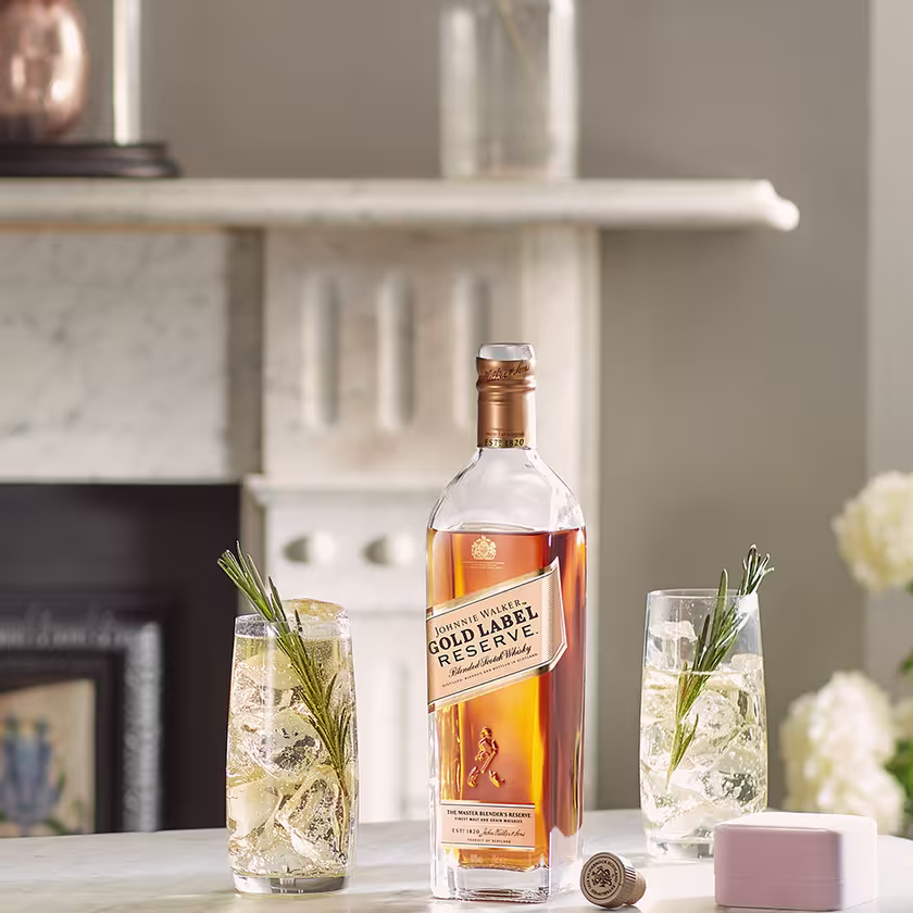 La imagen muestra una botella de whisky Johnnie Walker Gold Label Reserve junto a dos vasos con cócteles preparados con este destilado.