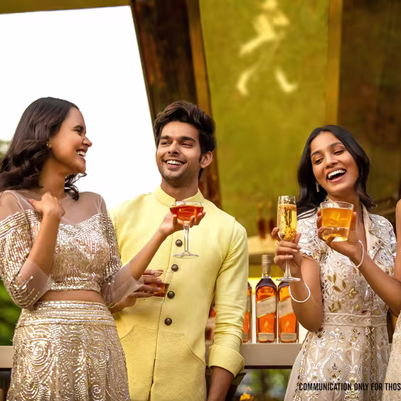 Cuatro personas sostienen diferentes cócteles mientras, en el fondo difuminado, se observan botellas de whisky Johnnie Walker Gold Label Reserve.
