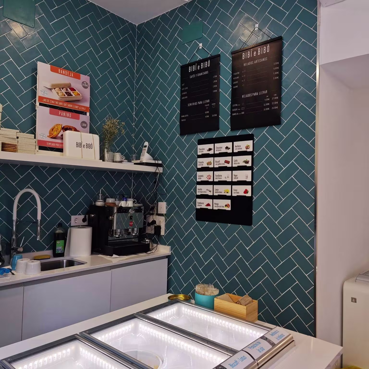 Zona de servicio de Bibi e Bibò Príncipe de Vergara con vitrinas de helado, carta en pared y azulejos en espiga azul.