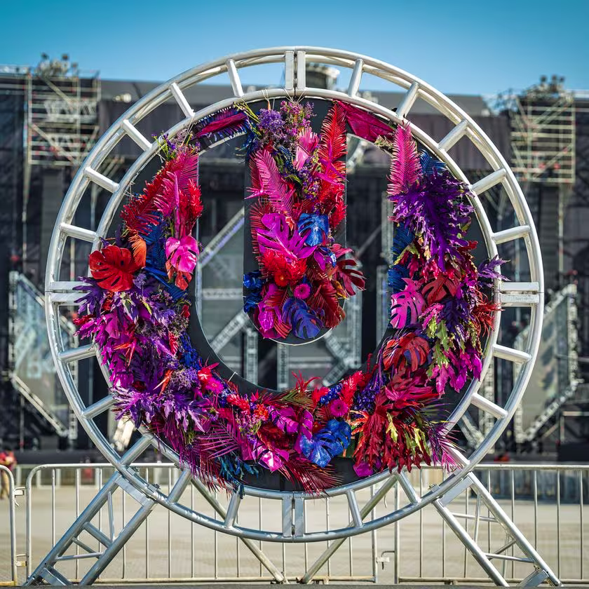 En la imagen se ve el logo de Ultra, relleno con flores y hojas en tonos rojos, fucsias, azules y violetas. De fondo el escenario, sin gente.