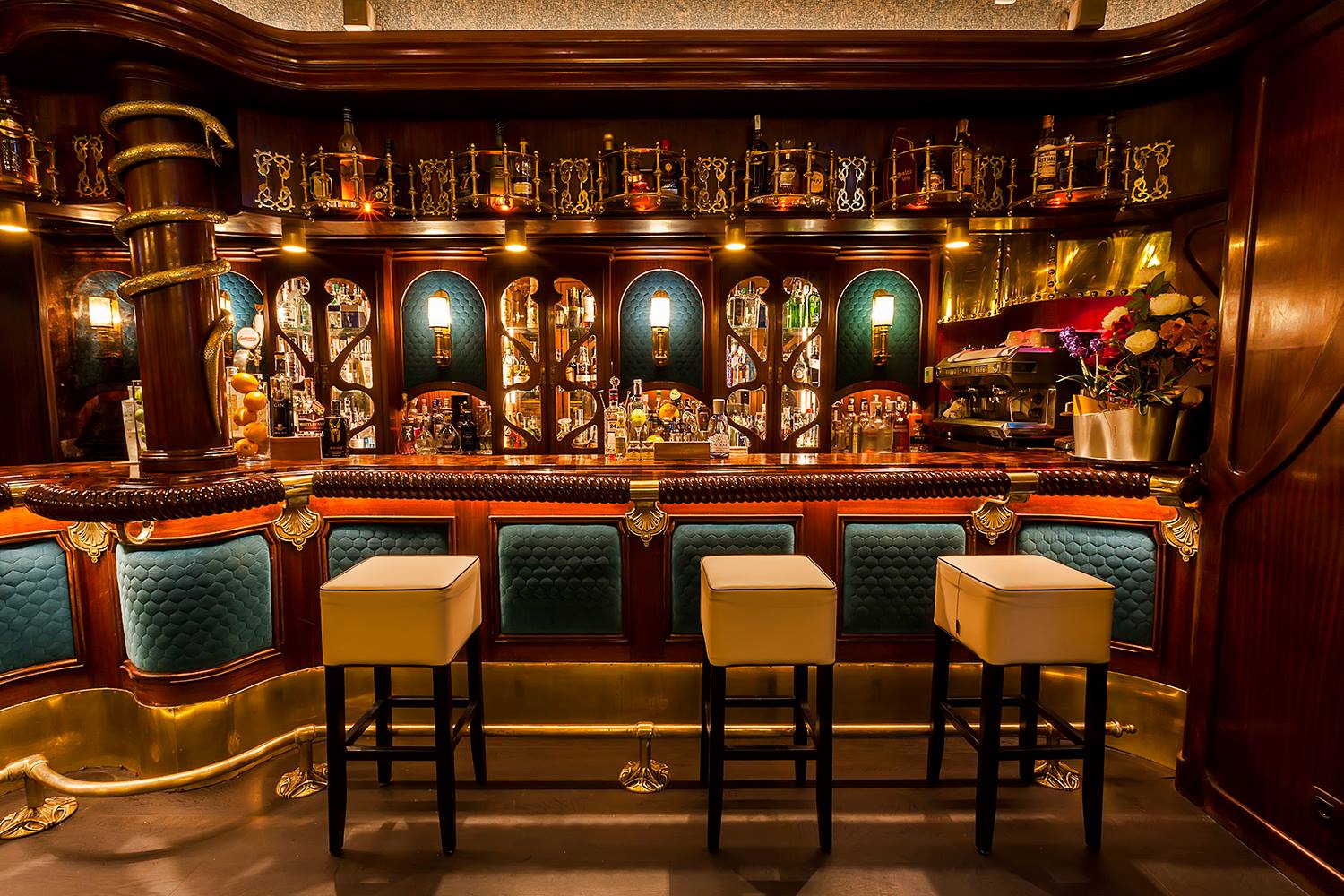 Bar Basque con su elegante barra de madera, detalles dorados y asientos acolchados, ofrece un diseño clásico y sofisticado.