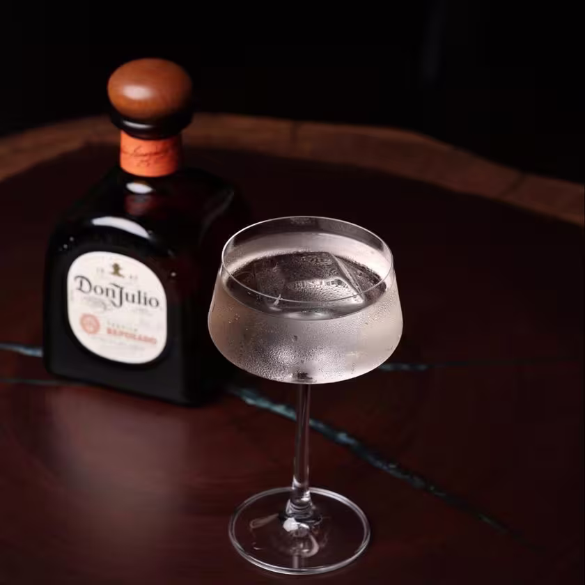 La imagen muestra una botella de Tequila Don Julio Reposado junto a una copa con el cóctel "Written in the Stars".