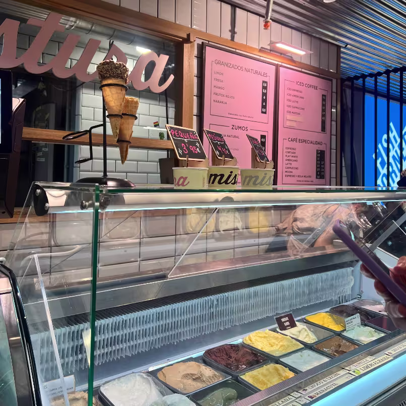 Vitrina de Mistura en el Mercado de San Antón con cucuruchos decorativos y helados artesanos en primer plano junto a cartelería en tonos pastel.