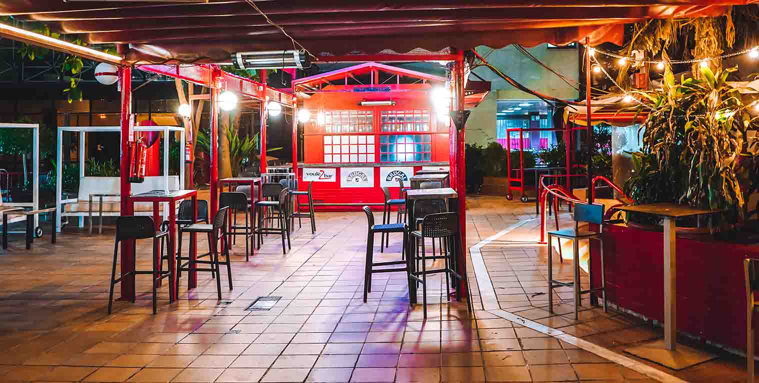 Voulezbar ofrece un espacio al aire libre vibrante y colorido, perfecto para disfrutar de copas, música y un ambiente relajado bajo las luces.