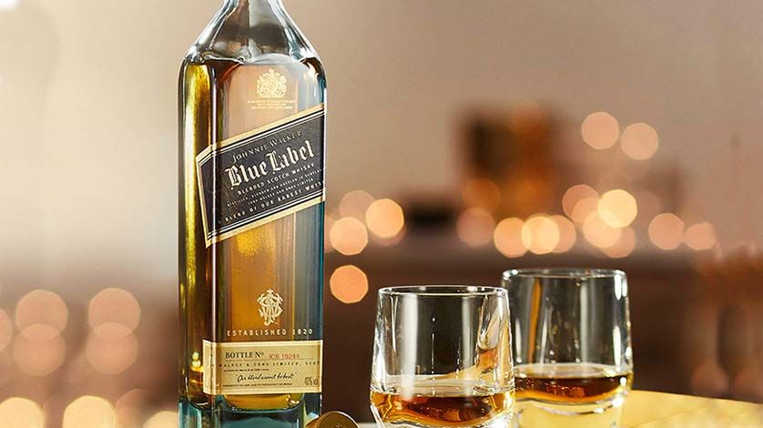 Botella de Jhonnie Walker Blue Label acompañada de dos vasos de whisky.