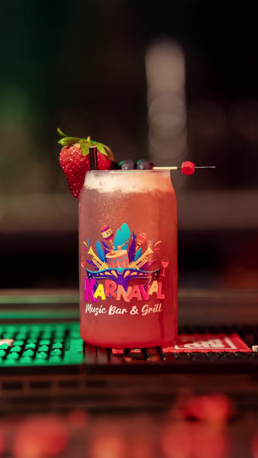 Karnaval Music Bar presenta un cóctel colorido y decorado con frutas frescas, reflejando su ambiente festivo y vibrante lleno de sabor y alegría.