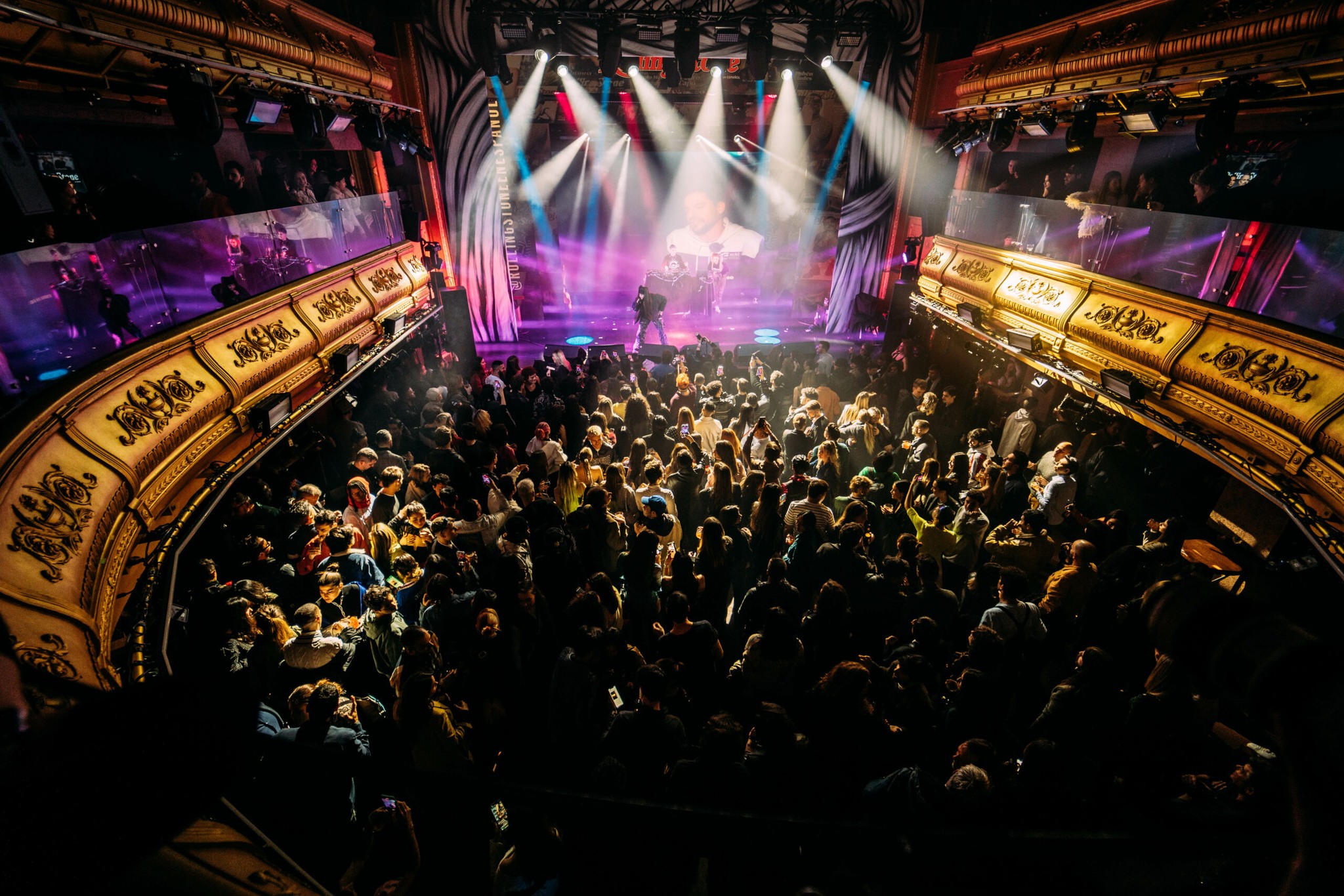 Ambiente vibrante en Teatro Eslava, con luces espectaculares y un público entregado disfrutando de una noche de música y entretenimiento.