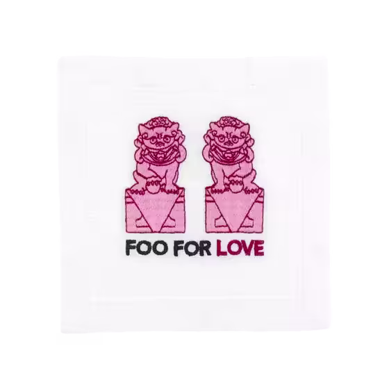 Two pink embroidered foo dogs sit on pedestals above the words FOO FOR LOVE, with LOVE in red, on a white fabric square.