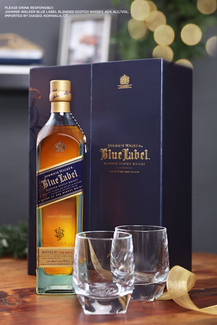 En la imagen se observa una botella de whisky Blue Label junto a su caja de empaque y dos vasos de whisky vacíos.