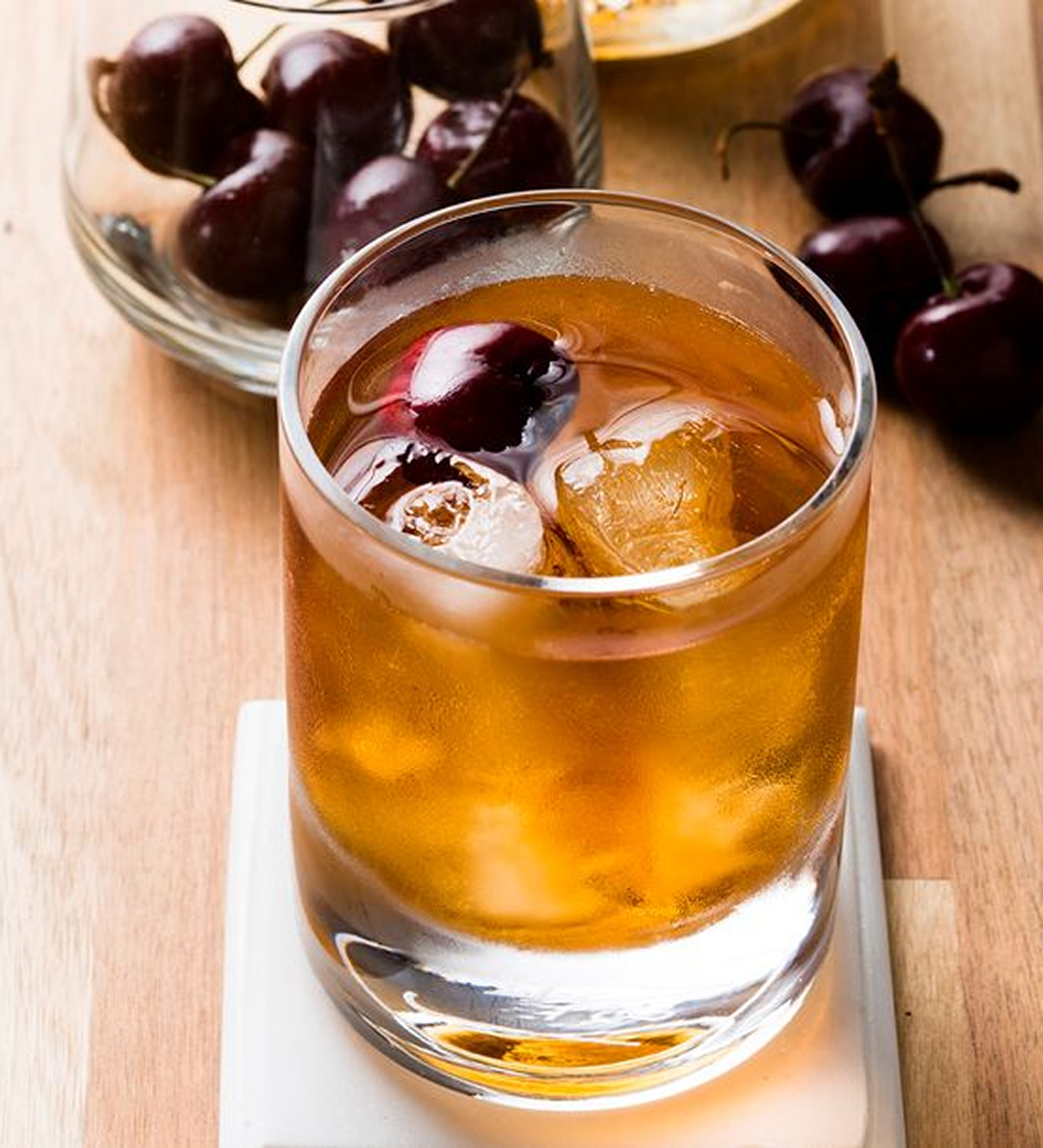 Whisky Sour cocktail made with Johnnie Walker Red Label, garnished with cherries on a wooden surface