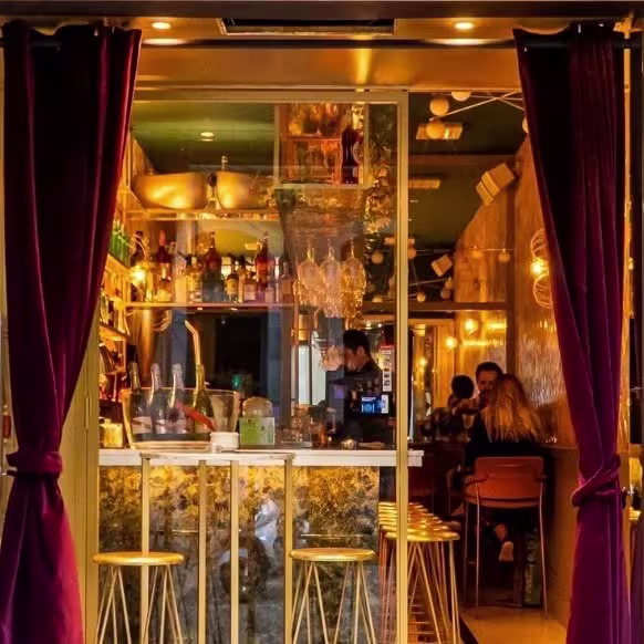 En La Perla, luces cálidas, cortinas aterciopeladas y un bar bien surtido crean una atmósfera acogedora y elegante para disfrutar.