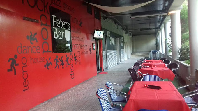 Terraza de Peter's Bar con mesas al aire libre y fachada roja decorada con estilos musicales, ideal para relajarse y socializar.