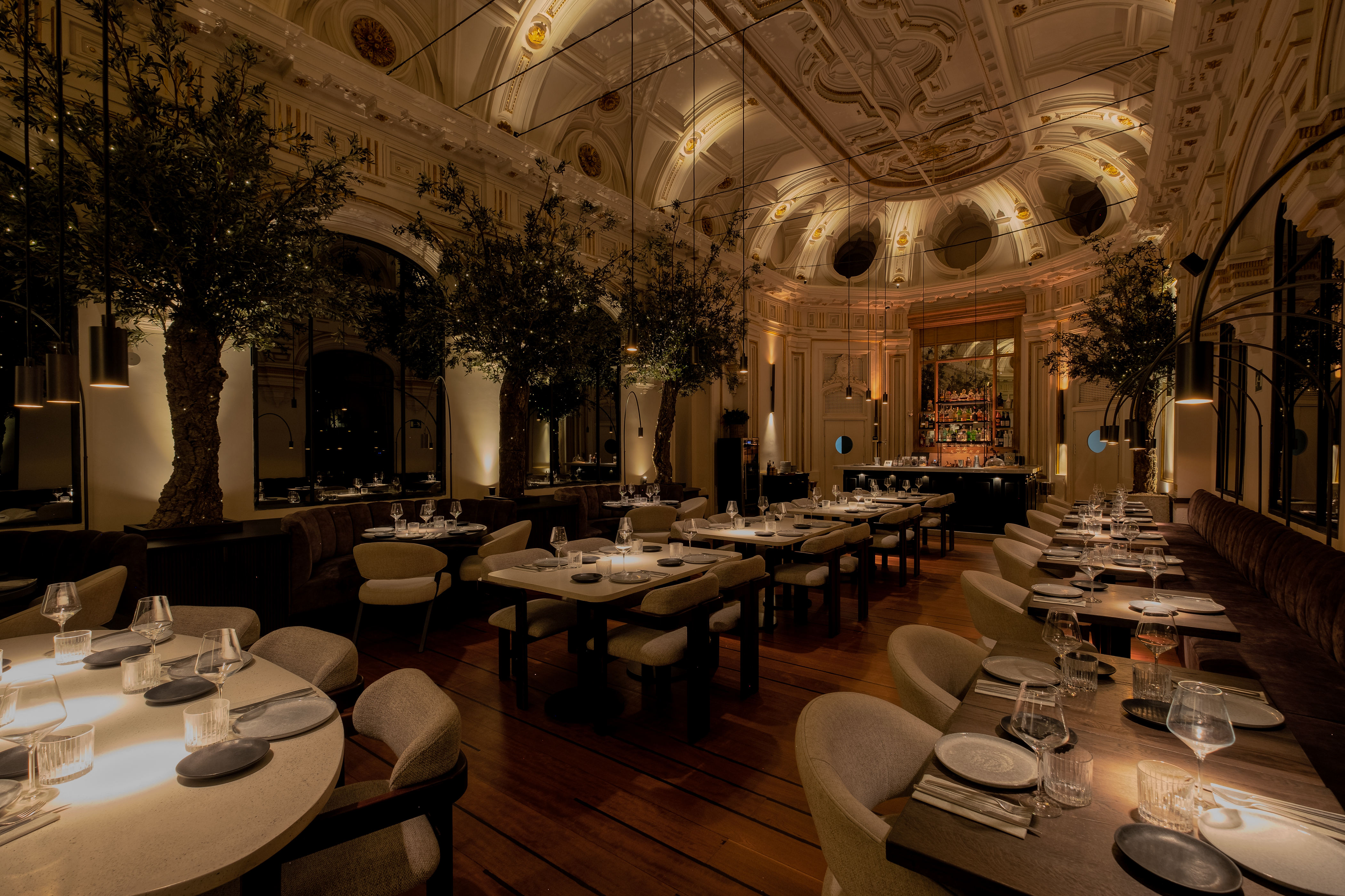 La imagen muestra el elegante comedor de Caluana.La sala cuenta con techos ornamentados con intrincados trabajos de yeso y una iluminación cálida que crea un ambiente acogedor. 