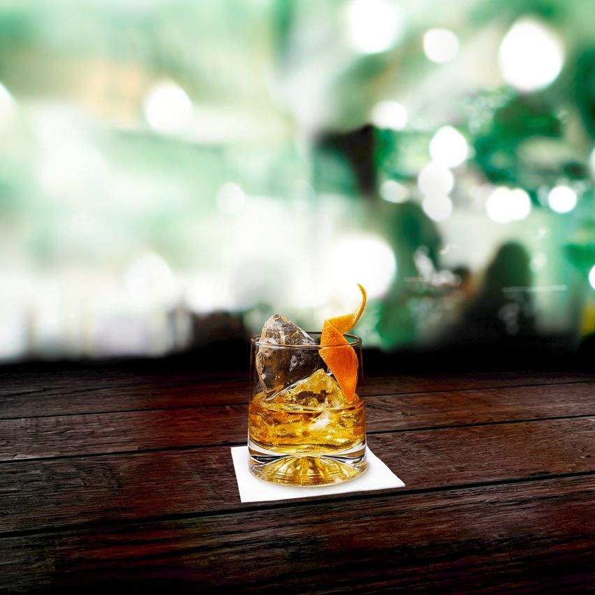 Whisky en las rocas con cascara de naranja como decoración.