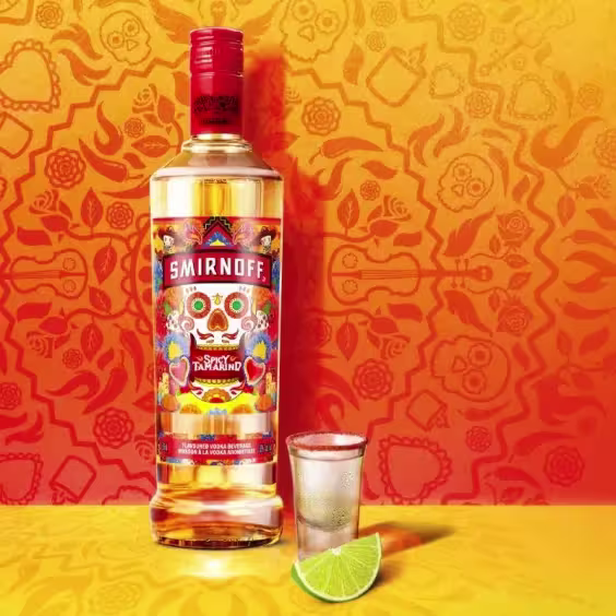 Botella de Smirnoff Spicy Tamarind con un shot y un gajo de Lima