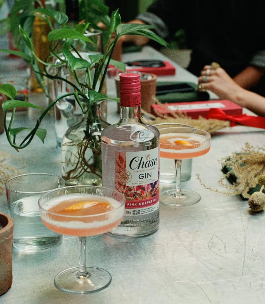 Chase Pink Grapefruit & Pomelo Gin bottle with two spritz cocktails garnished with grapefruit slices, served on a marble tray.