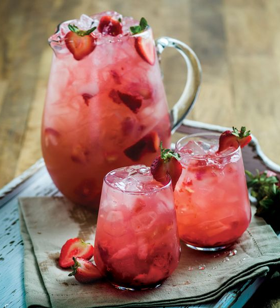 Gordon’s Pink Gin Spritz in a large pitcher with ice and strawberry garnish, served in glasses