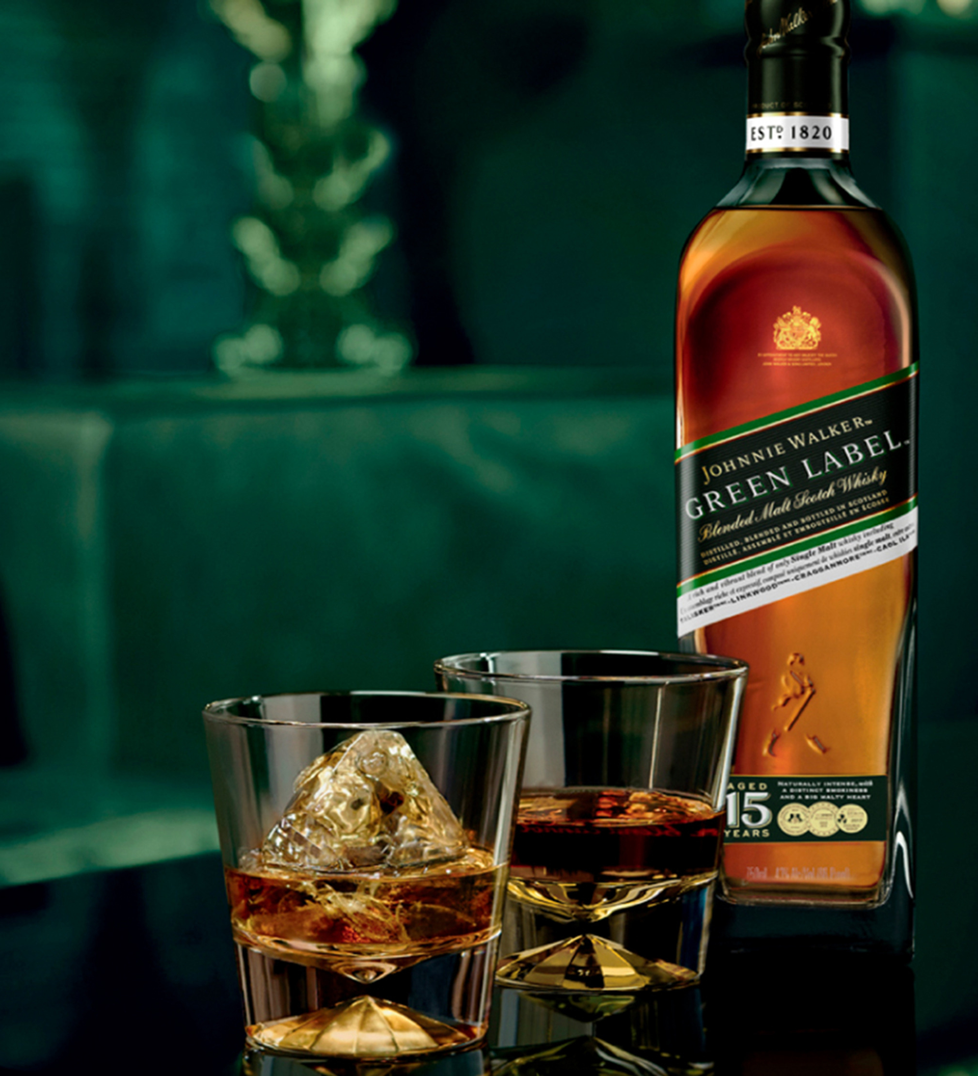 Johnnie Walker Green Label bottle with two Old Fashioned whisky cocktails on a dark bar counter