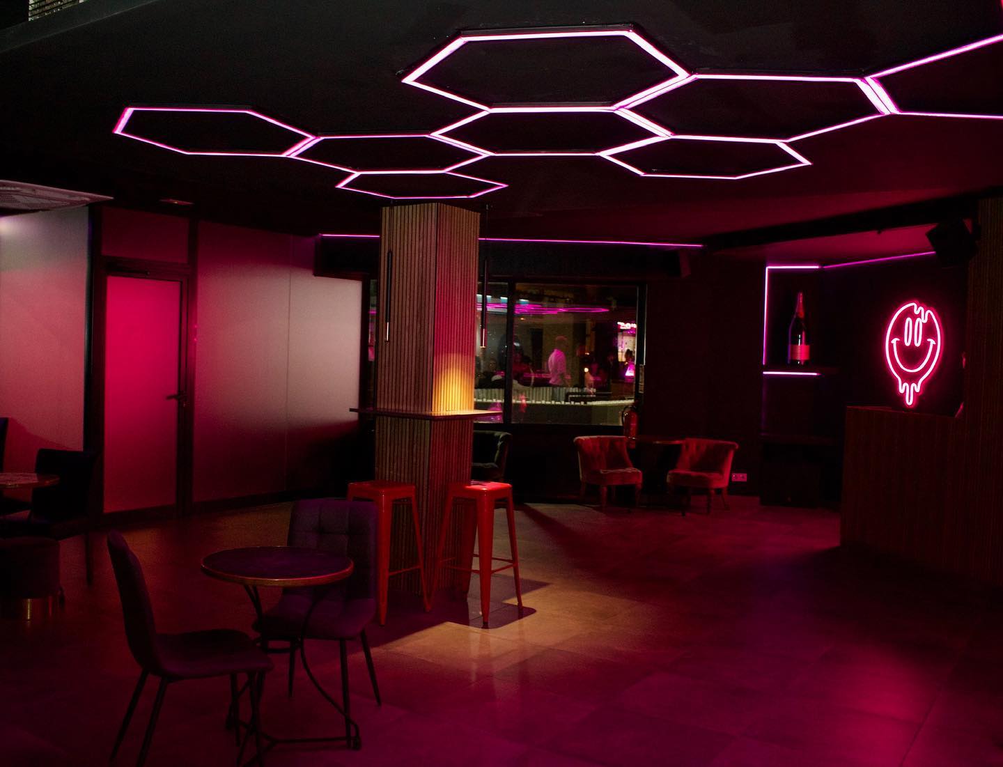 Espacio interior de Mobsters, con una estética vibrante destacada por luces de neón rosa y un diseño moderno.