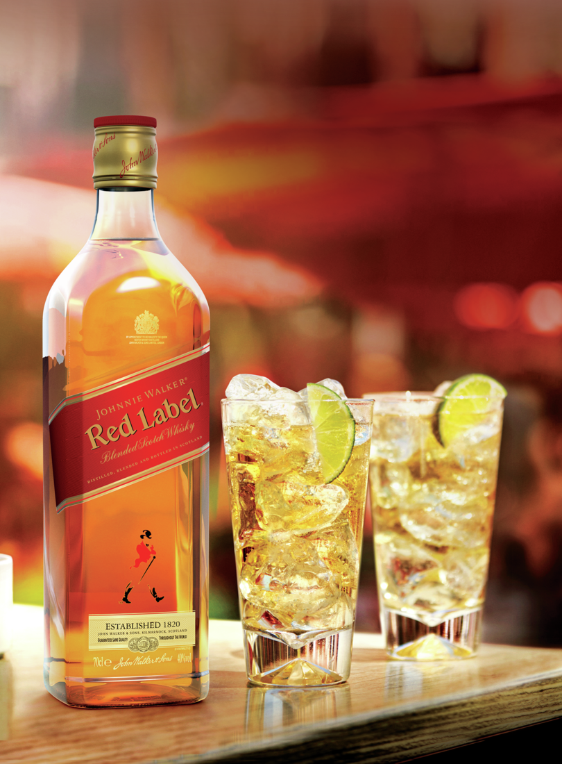 En la imagen se aprecia una botella de whisky Johnnie Walker Red Label junto a dos vasos highball con whisky, hielo y limón.
