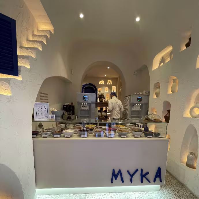 Interior de Myka San Lucas con mostrador de helados, paredes blancas abovedadas y hornacinas iluminadas.
