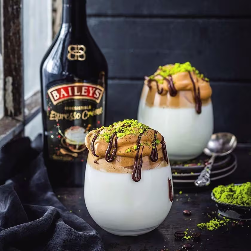 La imagen muestra dos vasos con el batido Dalgona Coffee y, al fondo, la botella de Baileys Espresso Créme.
