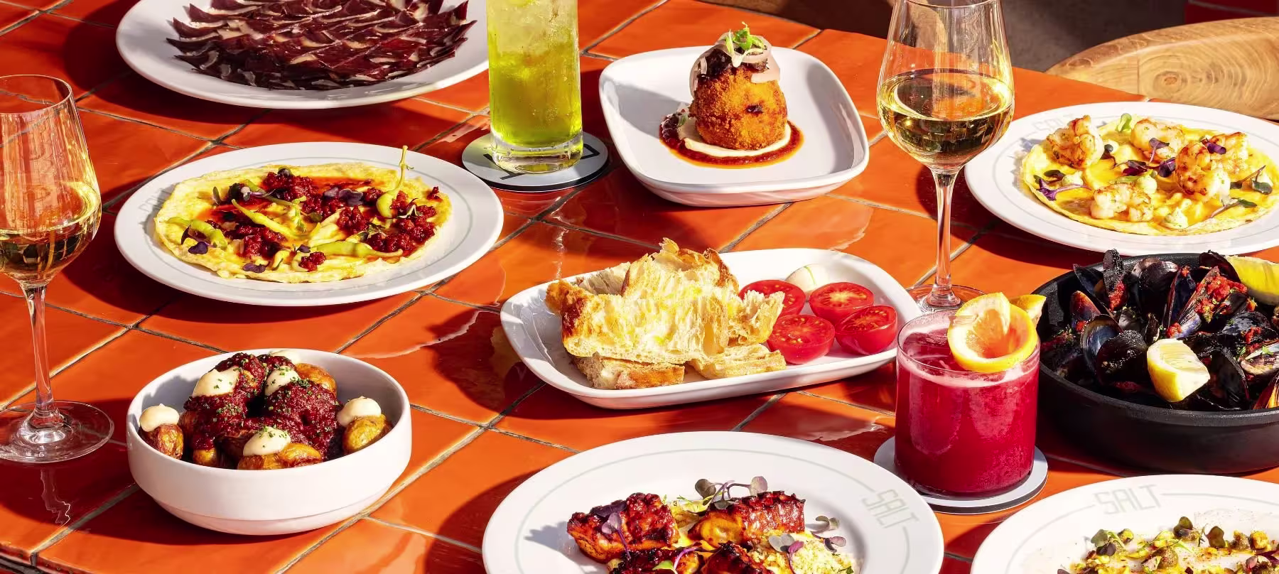 Un festín de sabores con platos frescos y deliciosos como camarones, mejillones, patatas, y una variedad de bebidas en SALT Restaurant & Beach Club.