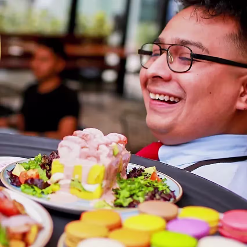 Mozo en Tanta con platos de torta y macarons