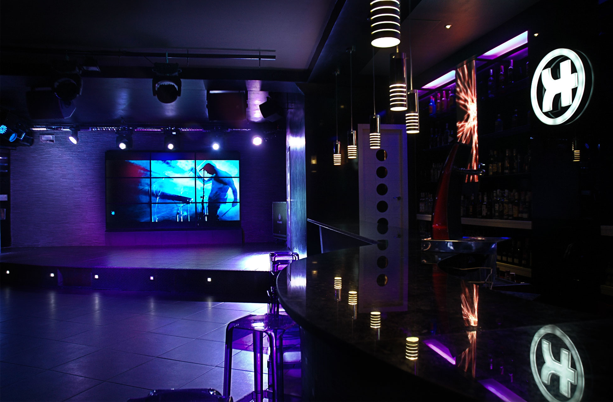 Interior de Sala Silikona con escenario iluminado, pantalla LED y barra moderna, ideal para eventos y música en vivo.