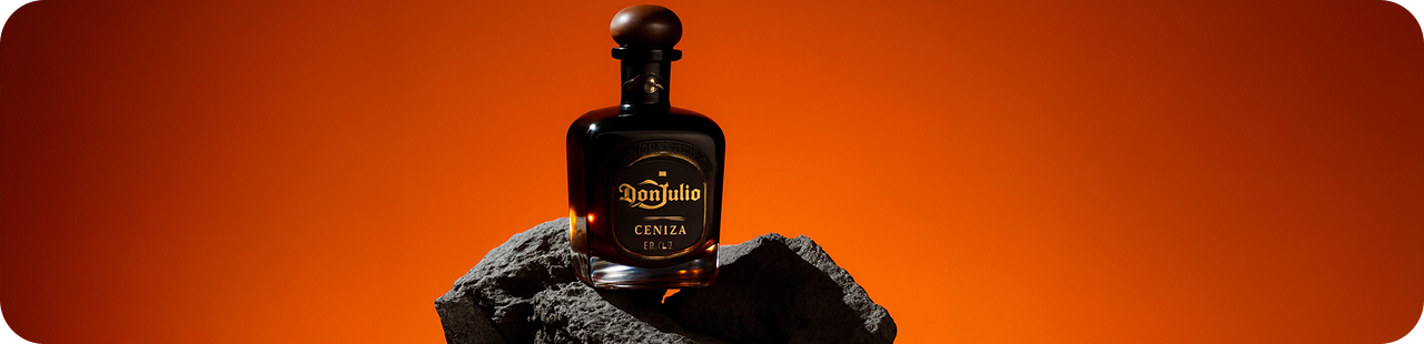 Botella de Don Julio sobre roca volcánica con fondo ámbar