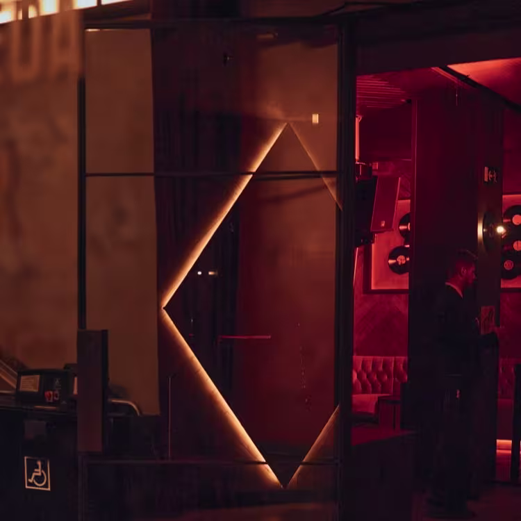La imagen muestra la entrada del Bardot Club, con una iluminación suave y un diseño moderno que invita a una experiencia exclusiva y única.