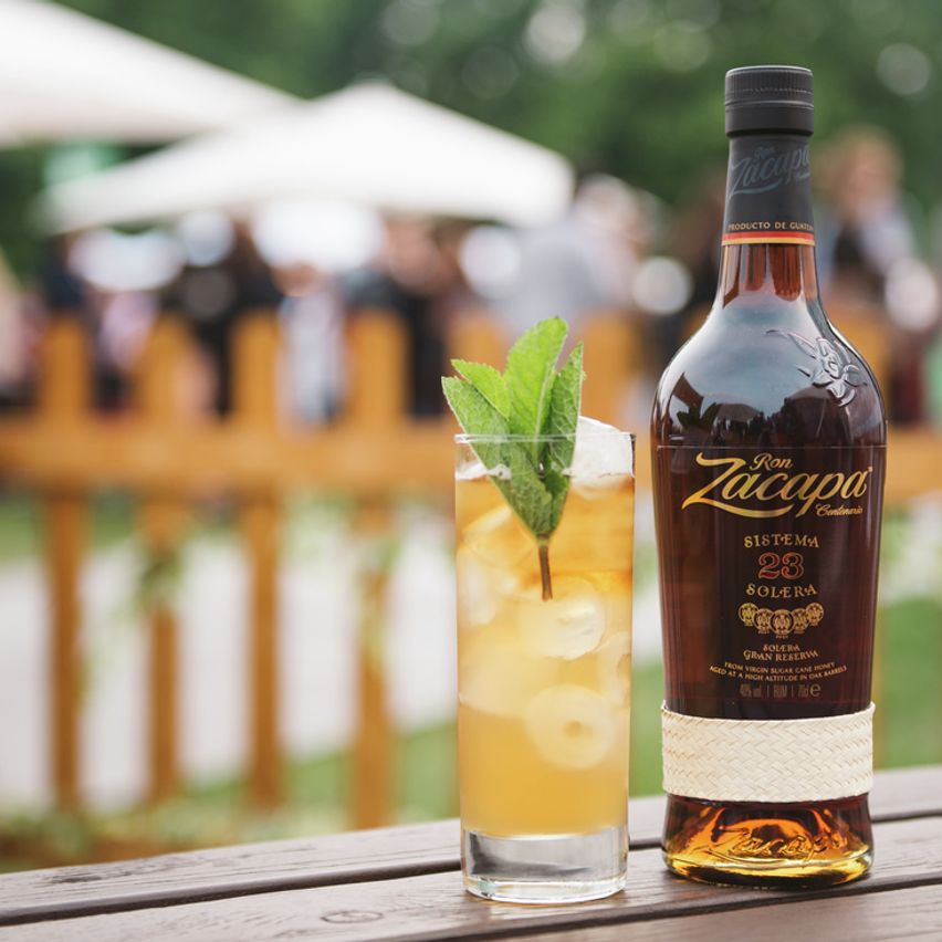 La imagen muestra una botella de ron Zacapa 23 junto a un vaso largo con un cóctel preparado con dicho destilado.