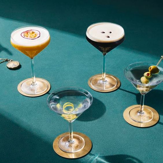 La imagen muestra cuatro copas rellenas con distintas variedades del cóctel martini.
