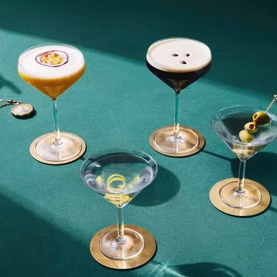 La imagen muestra cuatro copas rellenas con distintas variedades del cóctel martini.