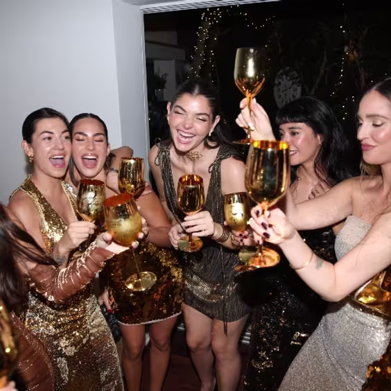 En la imagen se aprecia un grupo de chicas con vestidos dorados agarrando una copa dorada con Johnnie Walker Gold Label Reserve