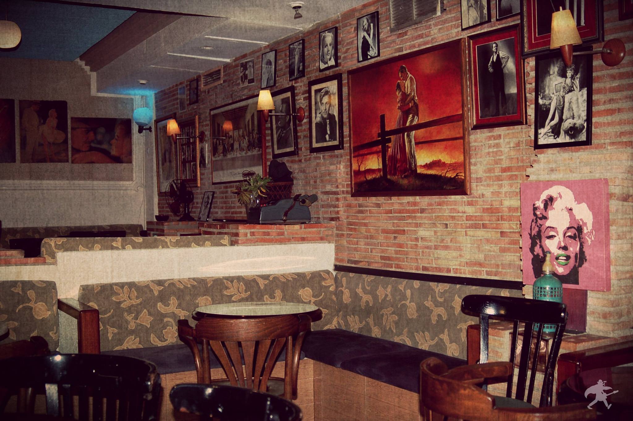 Interior de Christopher con paredes de ladrillo decoradas con retratos de leyendas del cine, sofás estampados y ambiente nostálgico de estilo clásico hollywoodiense.