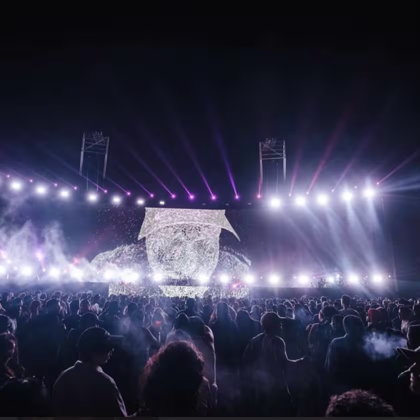 multitud de gente visualizando un espectáculo de luces blancas en el escenario