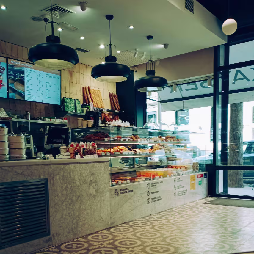Mostrador de mármol con panes y dulces, suelos hidráulicos y luz natural en Maison Kayser Zurbano.