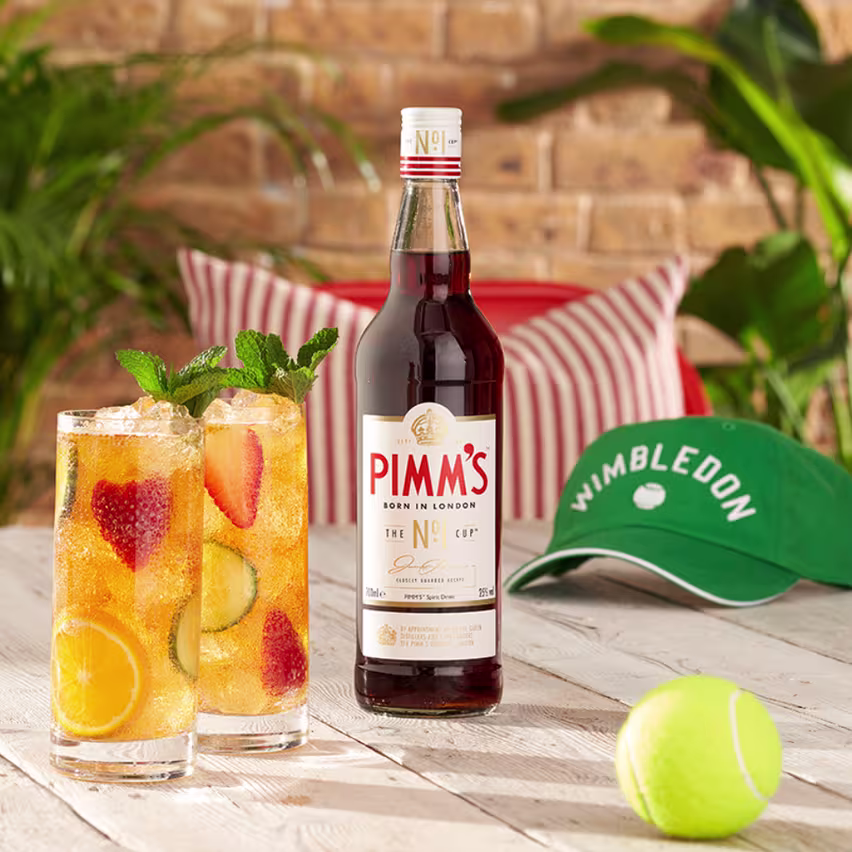 Jug of Pimm's with a Wimbledon cap and tennis ball pictured beside them