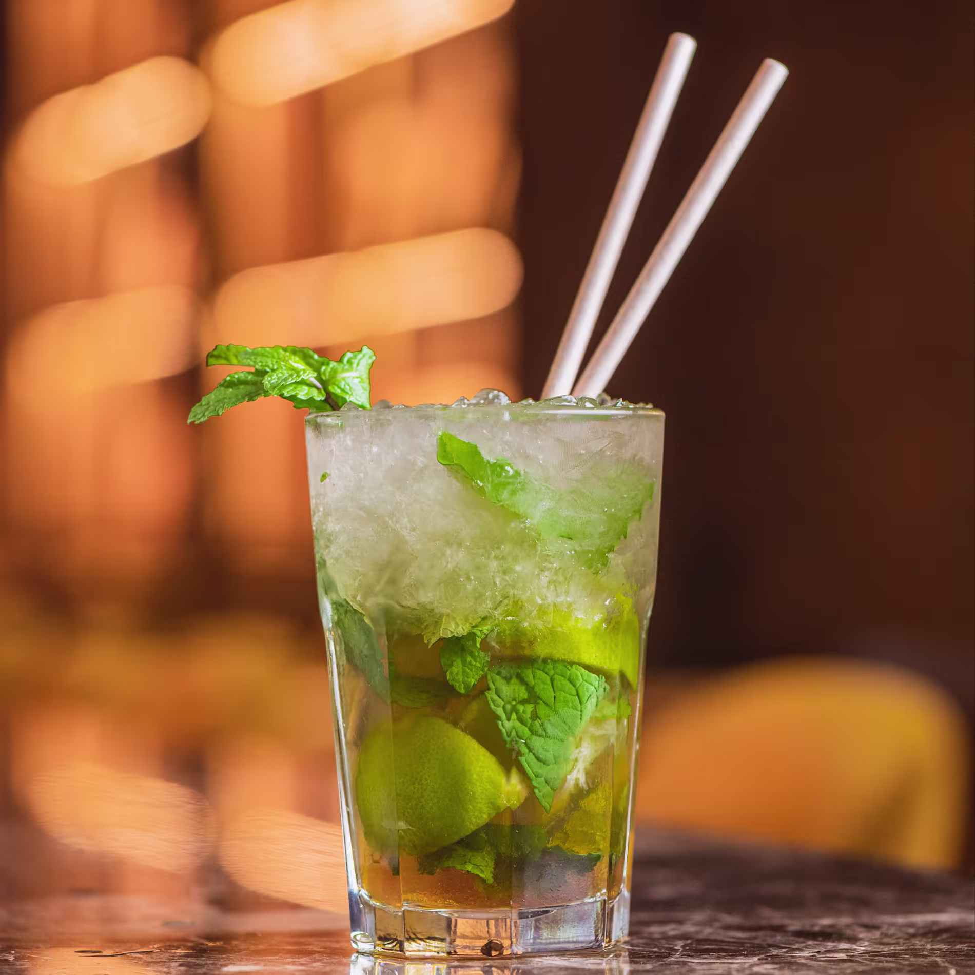Mojito con lima y hierbabuena servido con hielo picado en Ochenta Grados Pozuelo, en una atmósfera elegante y llena de reflejos dorados.