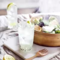 La imagen muestra una mesa con un plato de comida y dos vasos rellenos con cócteles preparados con vodka.