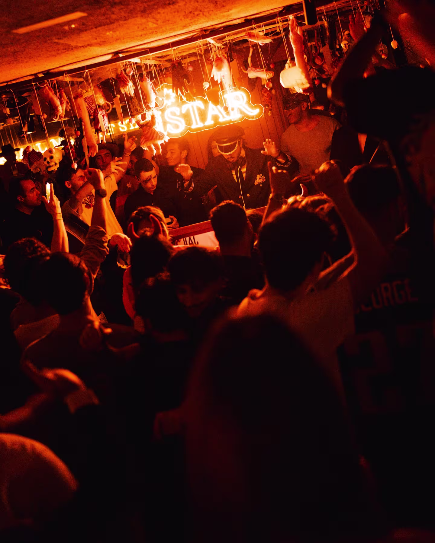 Fiesta vibrante en Istar Madrid, con DJ, iluminación cálida de neón y un público animado disfrutando de un ambiente nocturno energético.
