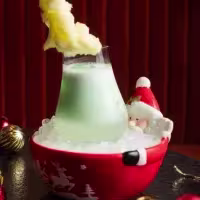 En la imagen se ve un coctel extravagante con dibujo de santa claus, y decoración navideña alrededor.